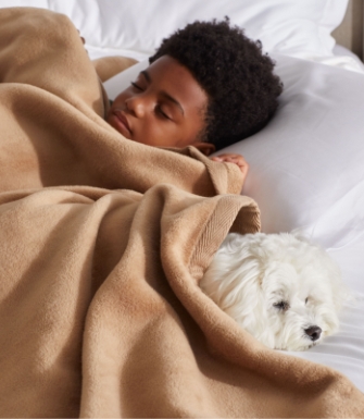 孩子盖着毯子和他的狗睡觉