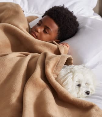 kid sleeping under blanket with his dog