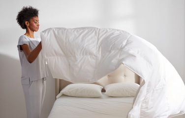 woman placing comforter on bed