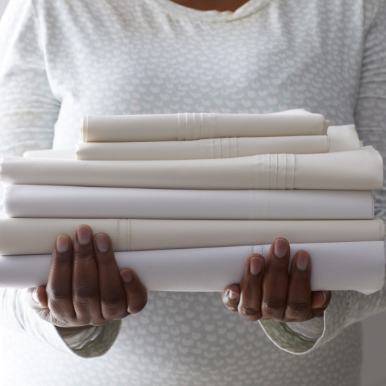 Woman holding stack of comforters